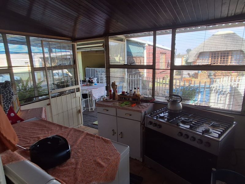 Enclosed patio area featuring a functional kitchen setup with a gas stove and built-in cabinetry, overlooking the rear garden space.
