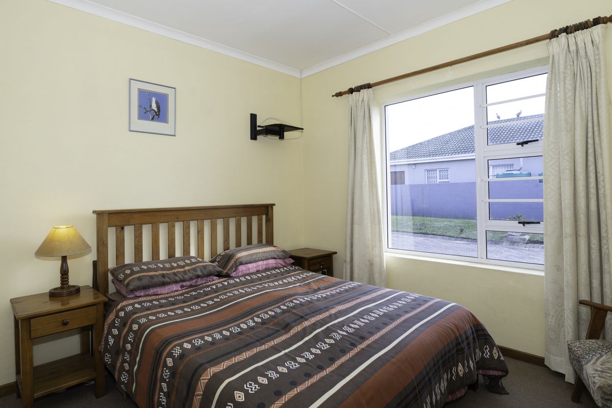 A well-lit bedroom featuring neutral walls, carpeted flooring, and a large window with views of the surrounding property.