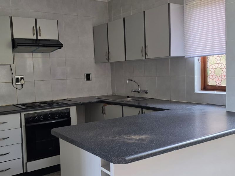 A functional kitchen featuring built-in cabinetry, a breakfast bar, and an electric stove, requiring minor repairs to cabinetry and surface finishes.