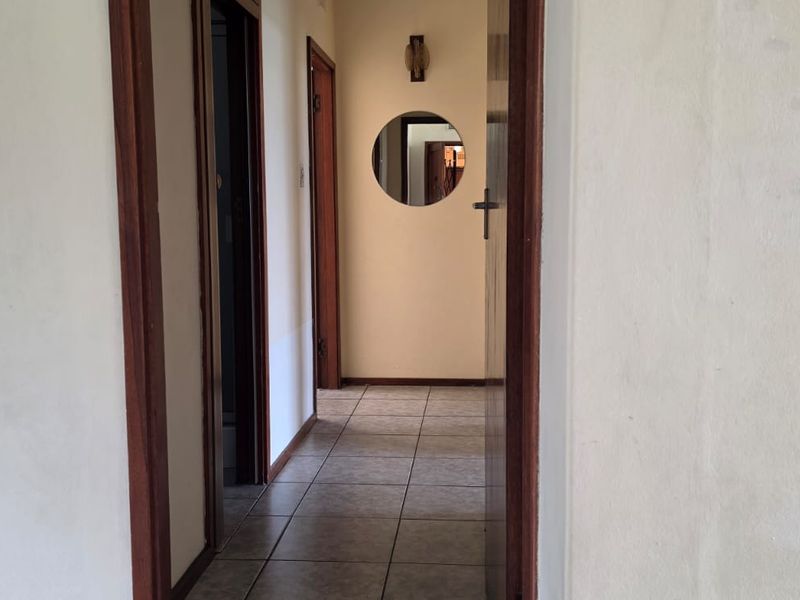 A functional hallway featuring tiled flooring and wooden door frames, connecting various rooms within the flat.