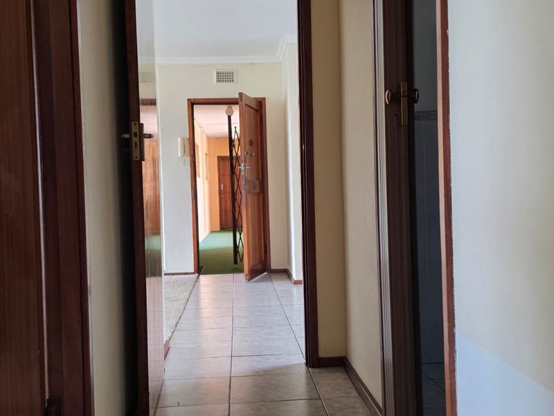 A functional hallway featuring tiled flooring and wooden door frames, providing access to various rooms within the flat.
