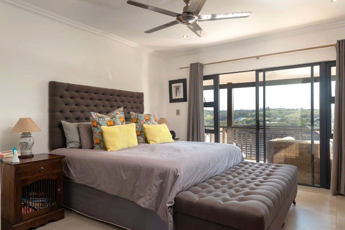 Spacious bedroom featuring a ceiling fan and large sliding glass doors that open onto a private balcony with scenic views.