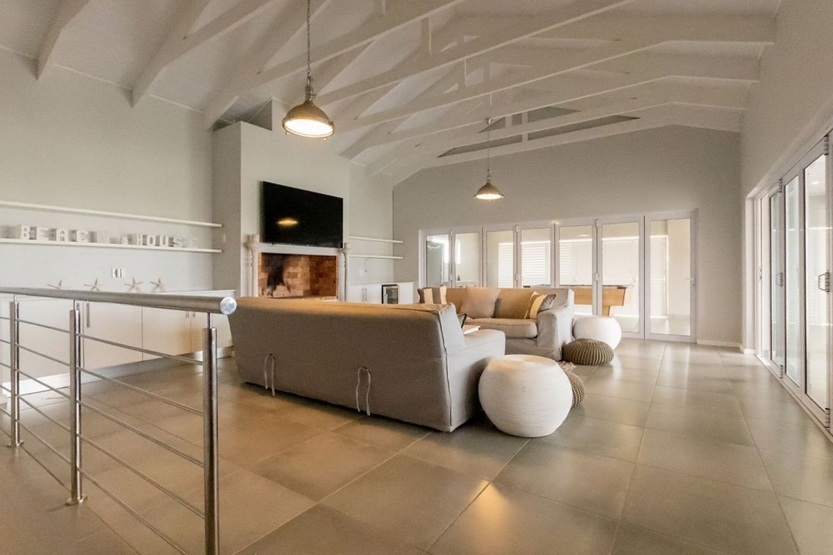 Spacious open-plan living area featuring vaulted ceilings, exposed beams, a built-in fireplace, and large glass sliding doors leading to an adjacent room.