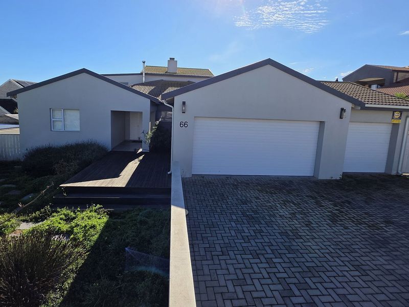 Front elevation of a modern house featuring a double garage, paved driveway, and a timber deck entrance area.