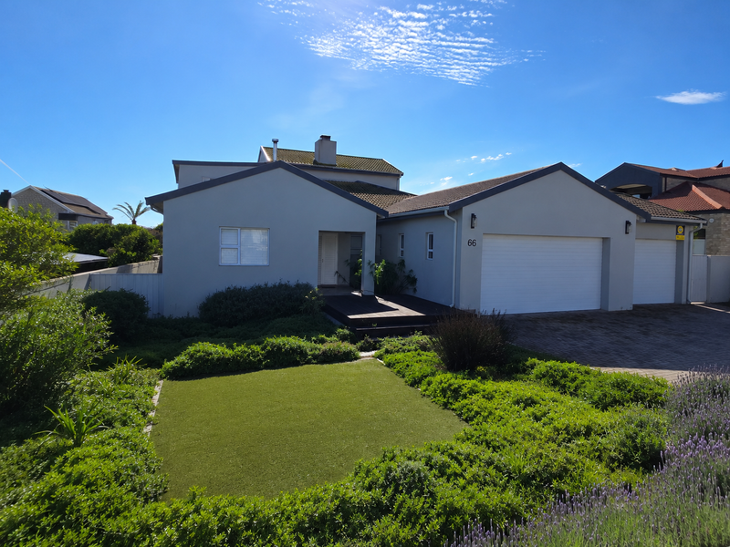A well-maintained modern single-story home featuring a double garage, paved driveway, and a neatly landscaped front garden with artificial turf.