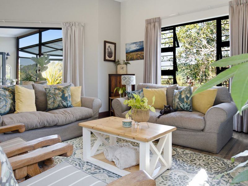 A bright and inviting living room featuring large windows that provide ample natural light and views of the surrounding greenery.