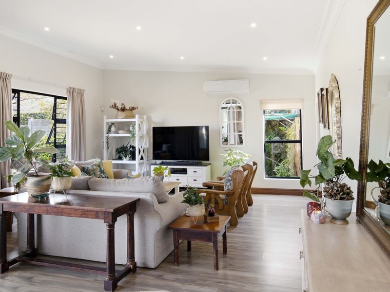 A bright and well-maintained living room featuring laminate flooring, recessed downlighting, and a wall-mounted split-system air conditioner.