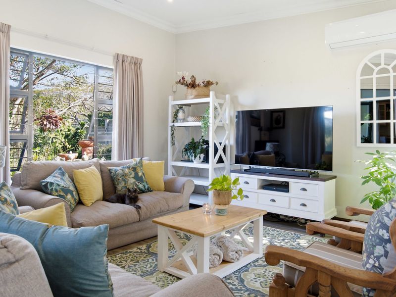 A bright and comfortable living room featuring a large window, split-system air conditioning, and decorative wall detailing.