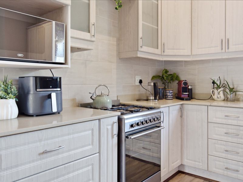 A well-maintained kitchen featuring light wood-grain cabinetry, stone countertops, a tiled backsplash, and a built-in microwave with a gas stove and oven.