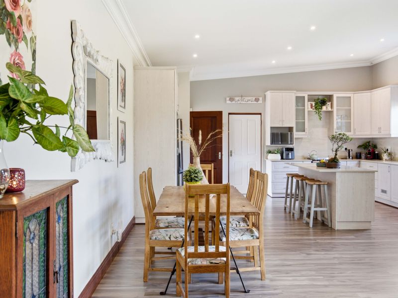 Spacious open-plan kitchen and dining area featuring light-toned cabinetry, a central kitchen island, and modern laminate flooring throughout.