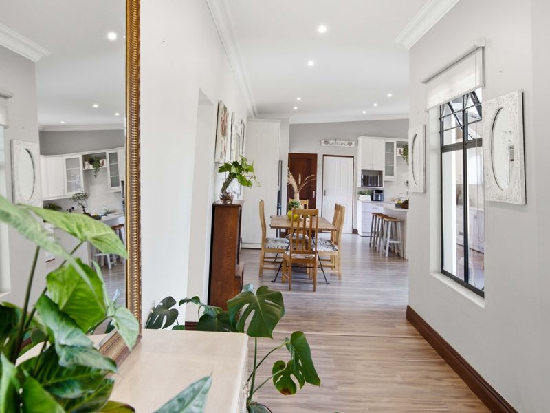 A bright open-plan living and kitchen area featuring modern laminate flooring, recessed lighting, and elegant crown molding throughout the space.