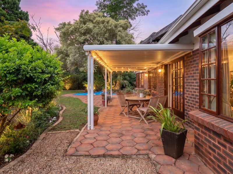 A well-maintained covered patio featuring brick paving and direct access to the garden and swimming pool area, perfect for outdoor entertaining.