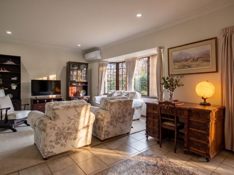 A spacious living room featuring tiled flooring, a large bay window, and a wall-mounted split-system air conditioner.