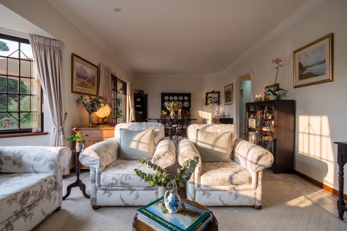 A warm and inviting living room featuring classic crown molding, tiled flooring, and large leaded glass windows that allow for abundant natural light.