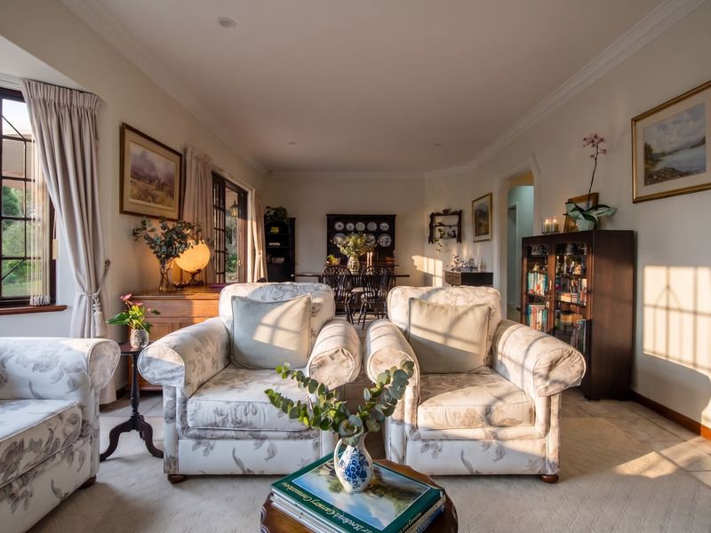 A warm and inviting living room featuring classic crown molding, tiled flooring, and large leaded glass windows that allow for abundant natural light.