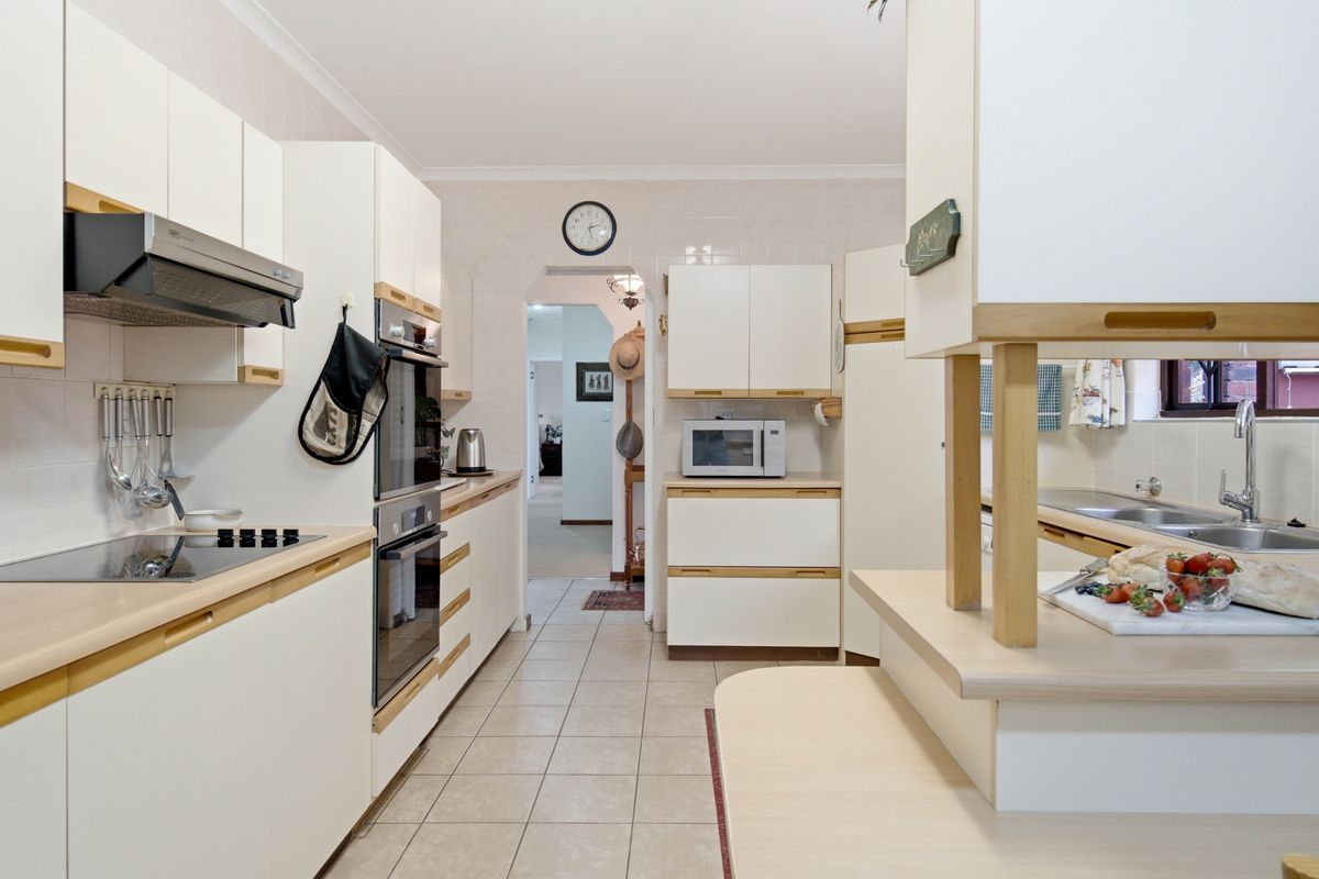 A functional kitchen featuring white cabinetry, laminate countertops, built-in oven, electric cooktop, and tiled flooring, offering a clean and practical workspace.
