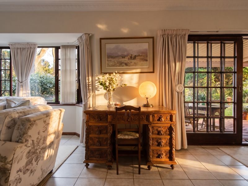 A sunlit living area featuring ceramic tile flooring, crown molding, a bay window, and classic french doors leading to an outdoor patio space.