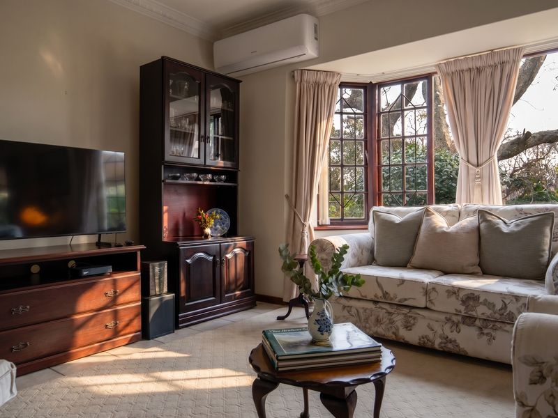 A cozy living room featuring a large bay window, crown molding, and a wall-mounted split-system air conditioner.