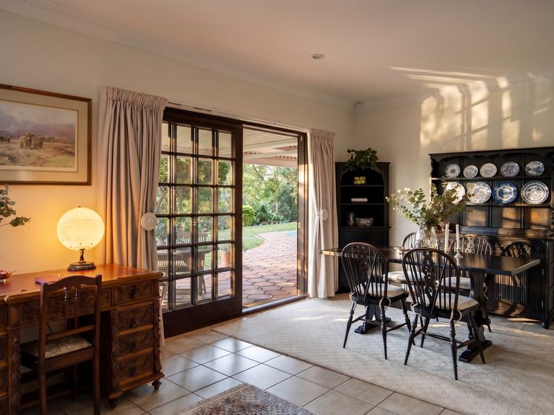 A bright dining room featuring ceramic tile flooring, crown molding, and large sliding glass doors that provide direct access to the outdoor patio area.
