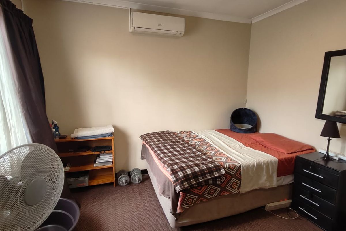 A bedroom featuring a wall-mounted air conditioning unit and carpeted flooring.