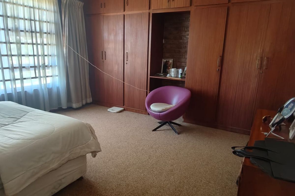A bedroom featuring extensive built-in wooden cabinetry, carpeted flooring, and a large window allowing natural light.