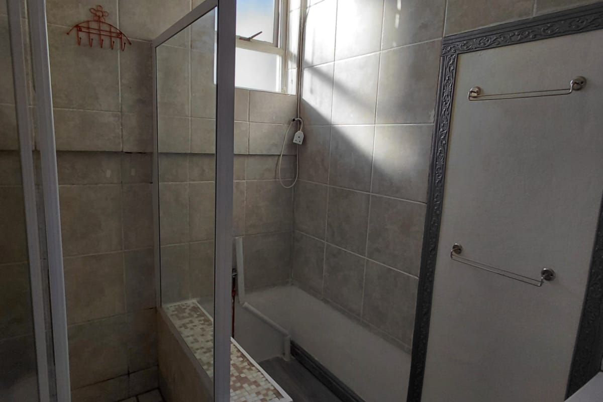 A functional bathroom featuring a walk-in shower with a built-in bench, tiled walls, and neutral flooring, offering a clean and practical layout.