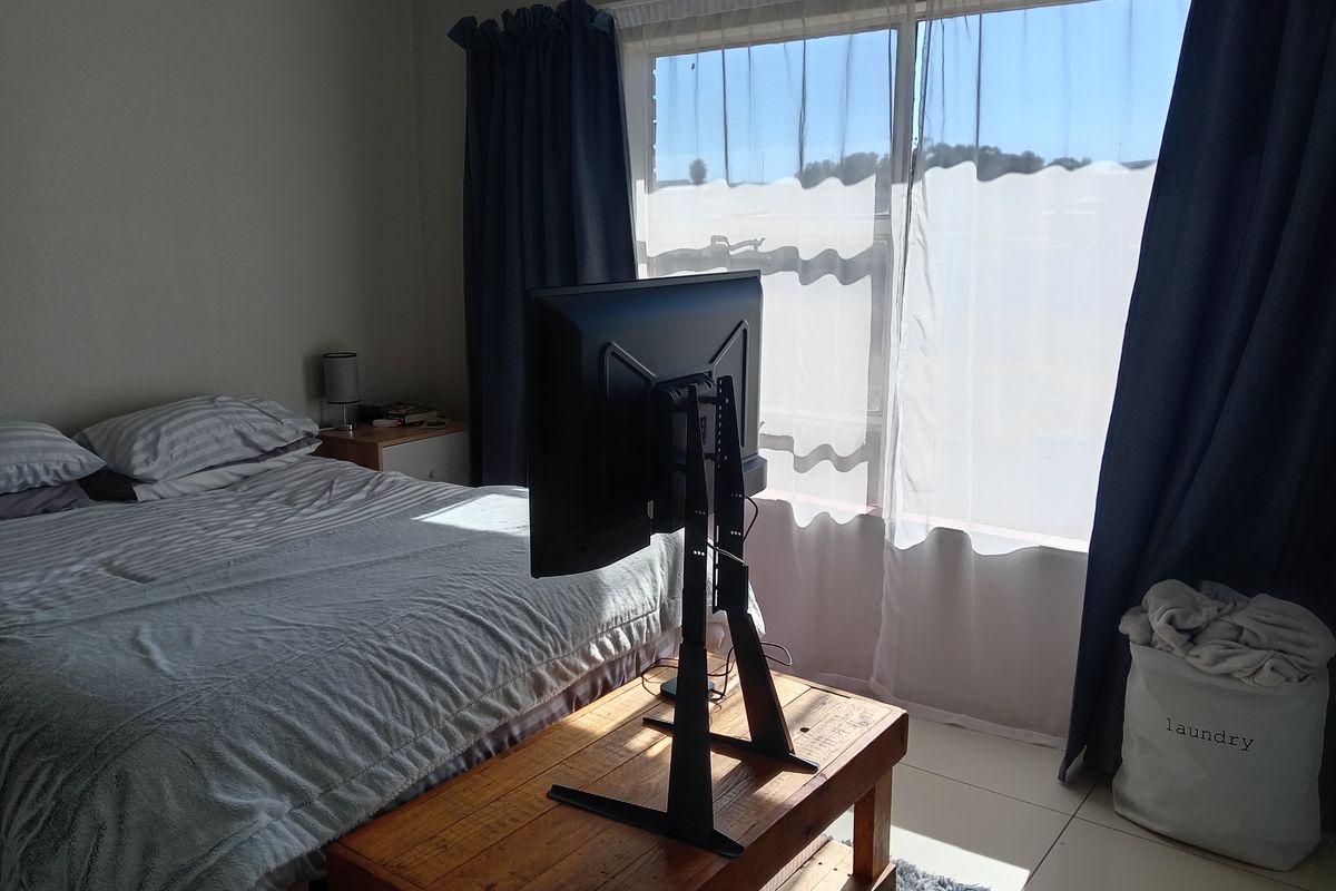 A bedroom featuring tiled flooring and a large window allowing natural light, providing a functional and comfortable living space.