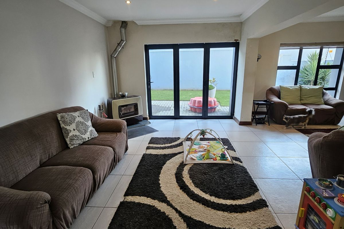 Spacious living room featuring tiled flooring, a freestanding fireplace, and bi-fold doors providing direct access to the rear garden area.