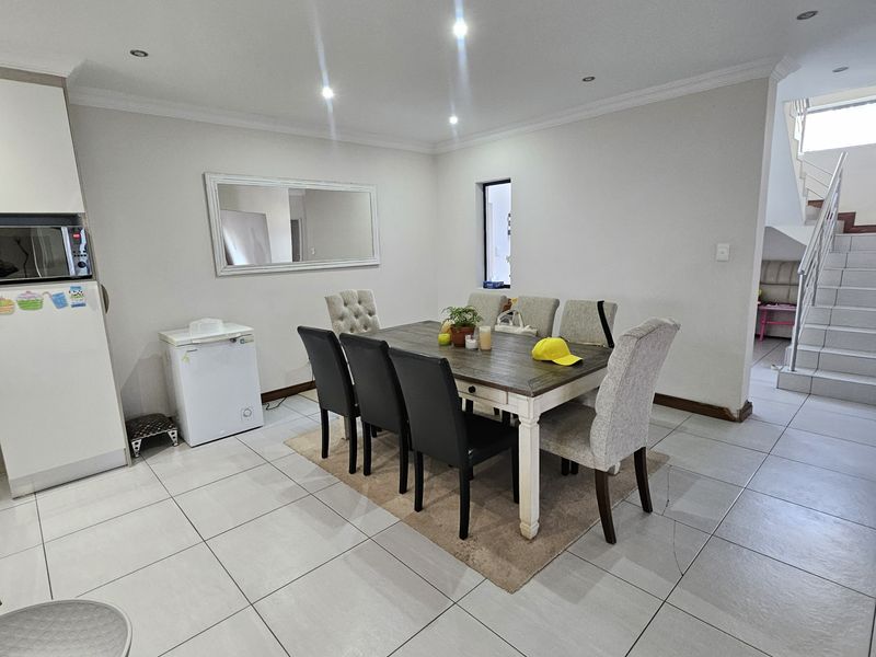 Open plan dining area featuring tiled flooring, recessed lighting, and a staircase with a modern metal railing.