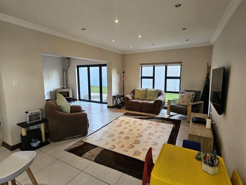 Spacious open-plan living area featuring tiled floors, recessed lighting, a wood-burning fireplace, and large aluminium-framed doors leading to the outdoor space.