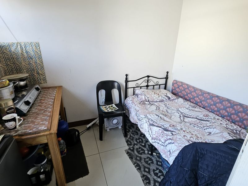 A compact bedroom featuring tiled flooring, currently utilized as a multi-purpose living space.