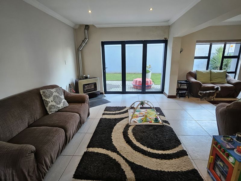 Spacious living room featuring tiled flooring, a freestanding fireplace, and bi-fold doors providing direct access to the rear garden area.