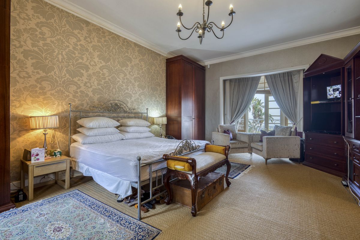 Spacious bedroom featuring patterned wallpaper, built-in wooden cabinetry, and access to a private balcony with scenic views.