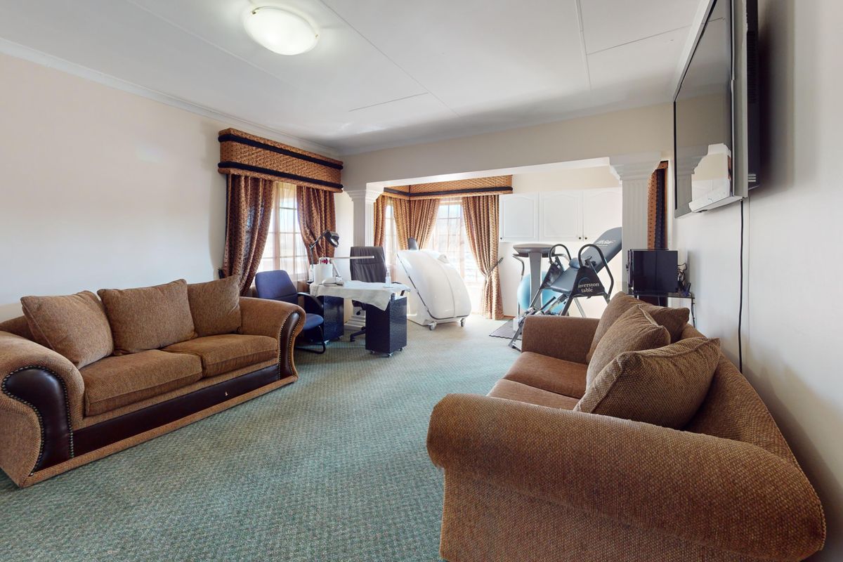 Spacious living area featuring a partition wall with columns, neutral wall finishes, and carpeted flooring, offering a versatile layout for various uses.