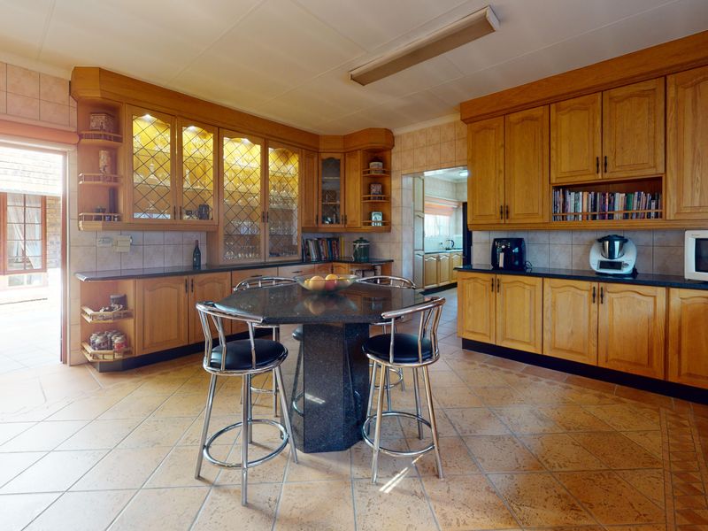 Spacious kitchen featuring extensive timber cabinetry, granite countertops, tiled flooring, and integrated display shelving with internal lighting.