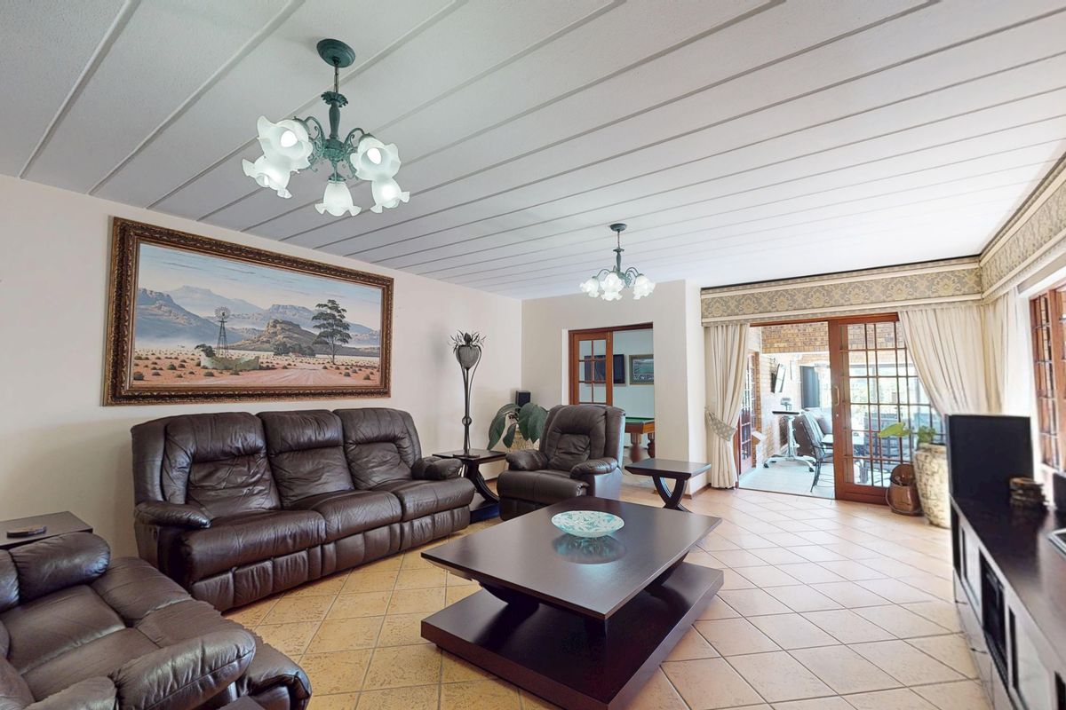 Spacious living room featuring tiled flooring, a panelled ceiling, and sliding glass doors providing access to an outdoor patio area.