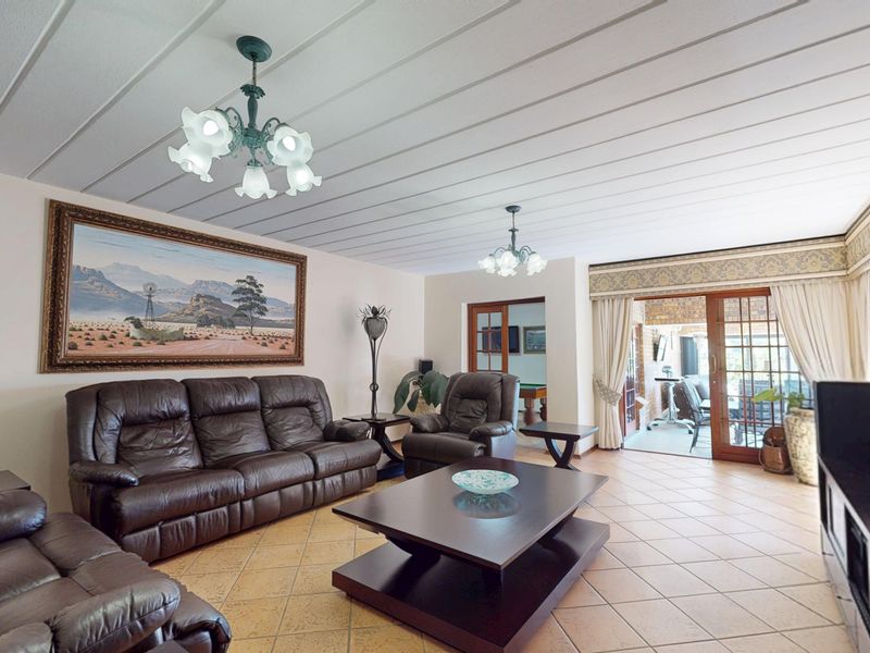 Spacious living room featuring tiled flooring, a panelled ceiling, and sliding glass doors providing access to an outdoor patio area.