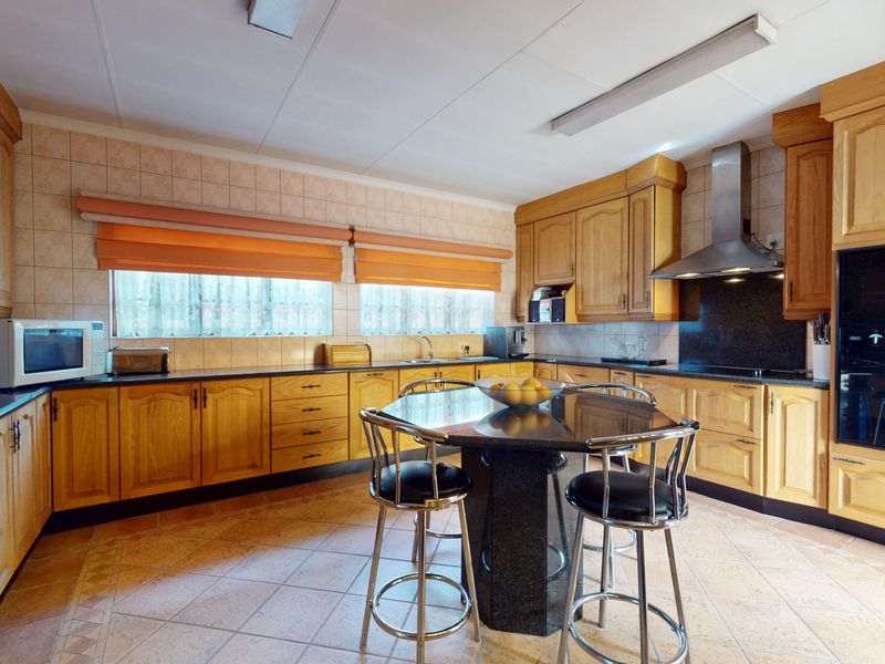 Spacious kitchen featuring traditional wooden cabinetry, granite countertops, integrated oven, stainless steel extractor fan, and tiled flooring with a central island.