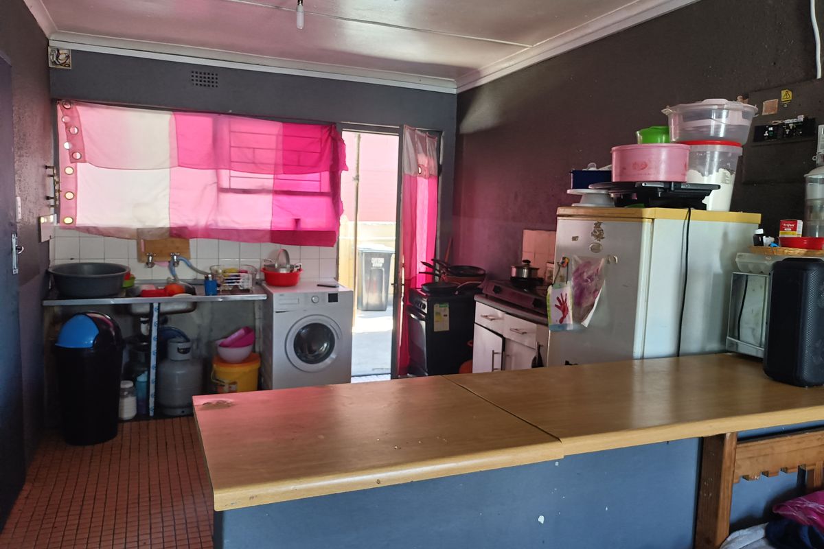 A functional kitchen area featuring a breakfast bar, stainless steel sink, and direct access to the exterior, offering potential for modernization.