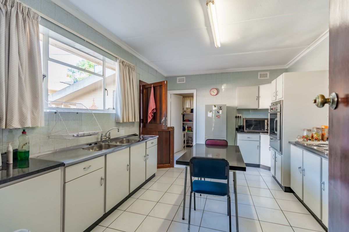 A functional kitchen featuring tiled flooring, a double stainless steel sink, built-in oven, and ample cabinetry, offering potential for modern renovation.