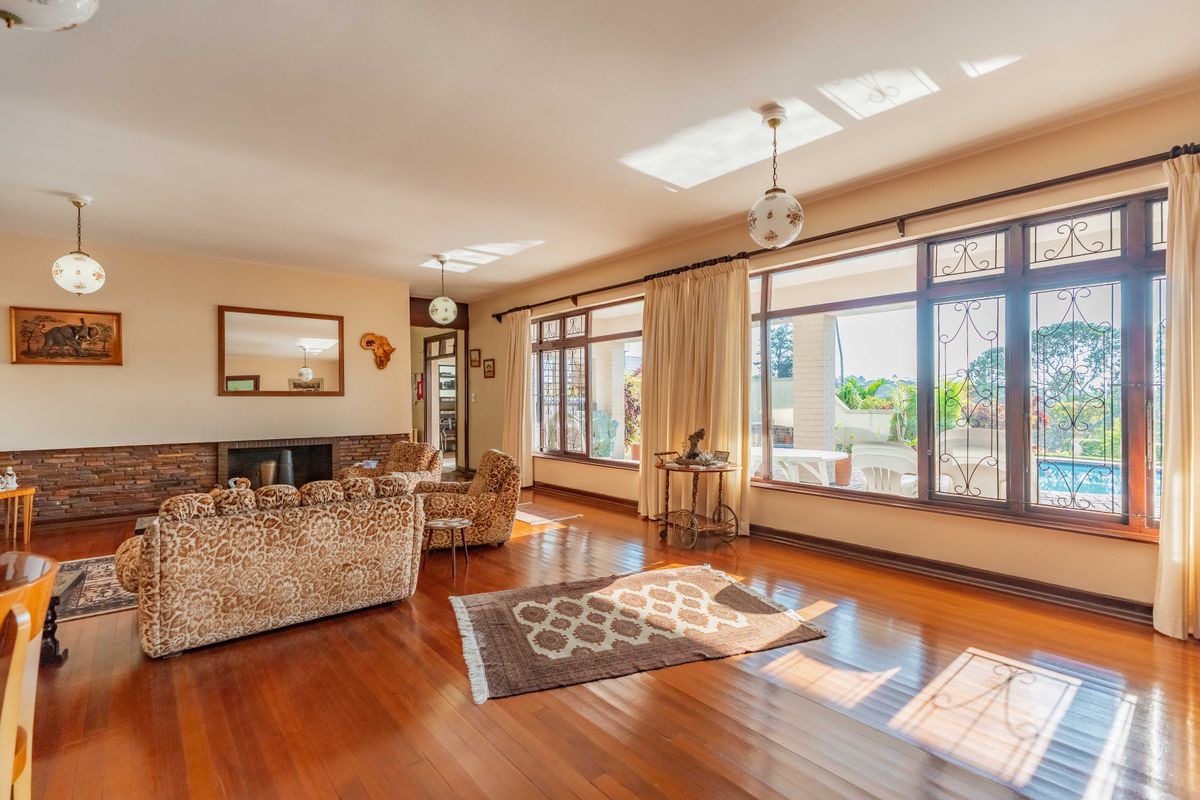 Spacious living room featuring polished hardwood floors, a stone-clad fireplace, and large windows that provide ample natural light and views of the outdoor area.