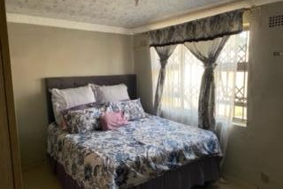A bedroom featuring a security gate on the window and a ceiling fan, requiring cosmetic updates to the ceiling and wall finishes.