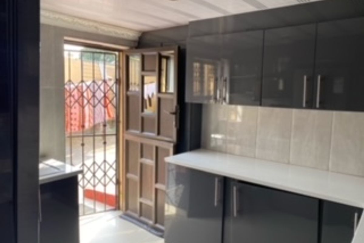 Modern kitchen featuring high-gloss cabinetry, stone countertops, and a tiled backsplash, with direct access to the exterior via a stable door and security gate.