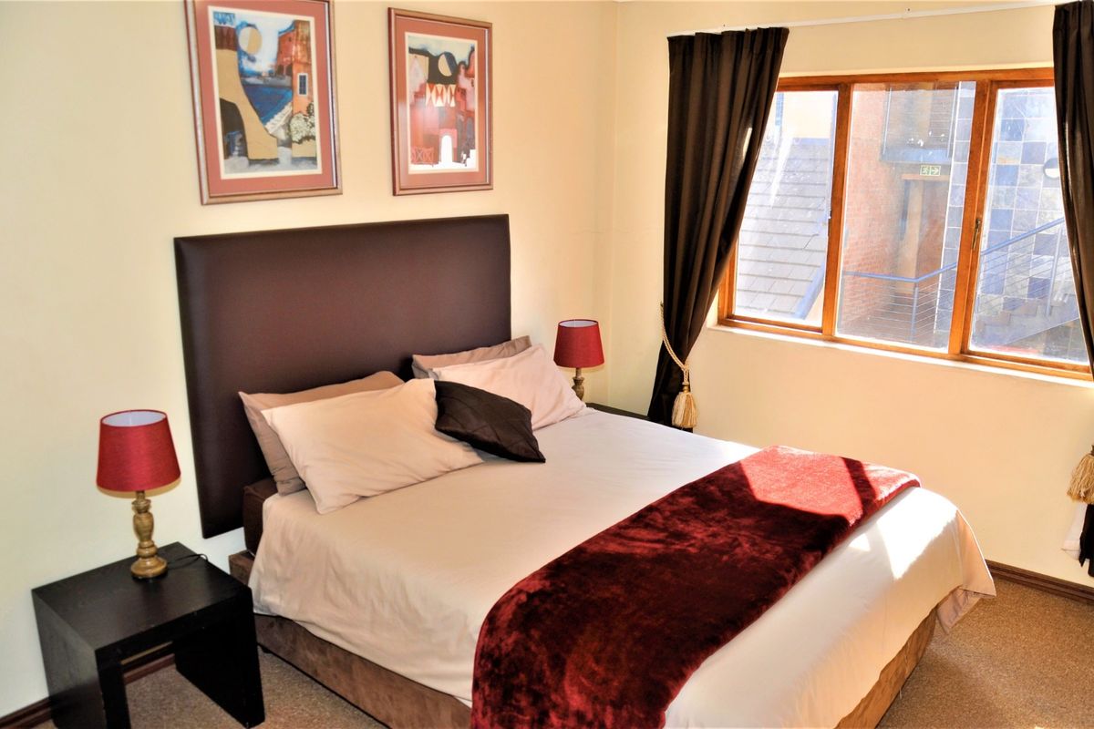 A cozy bedroom featuring a timber-framed window and neutral wall finishes, providing a comfortable and functional sleeping space.