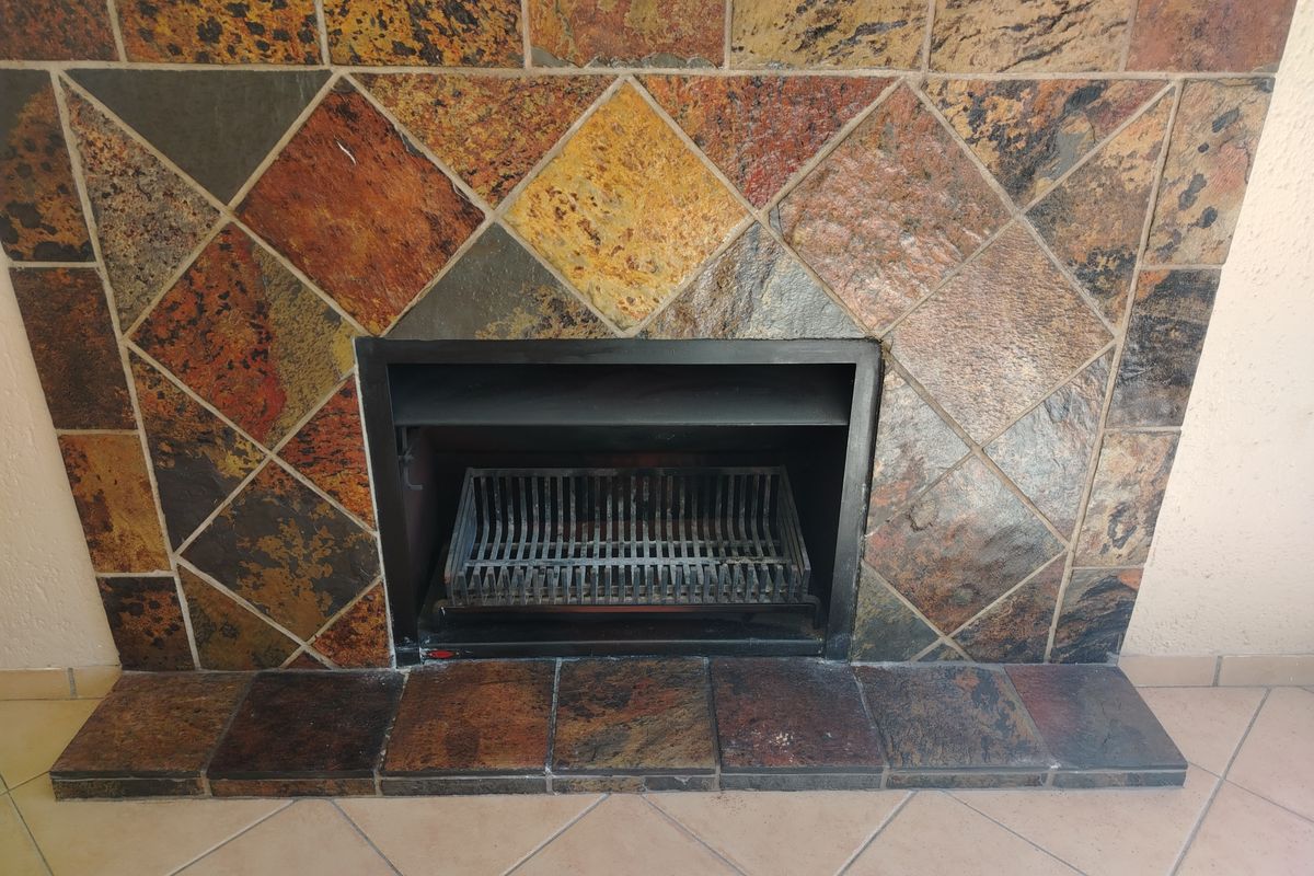 A built-in fireplace featuring a decorative multi-colored slate tile surround and a metal fire grate.