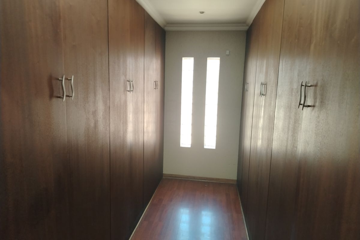 A walk-in closet or dressing area featuring extensive floor-to-ceiling built-in wooden cabinetry and laminate flooring.