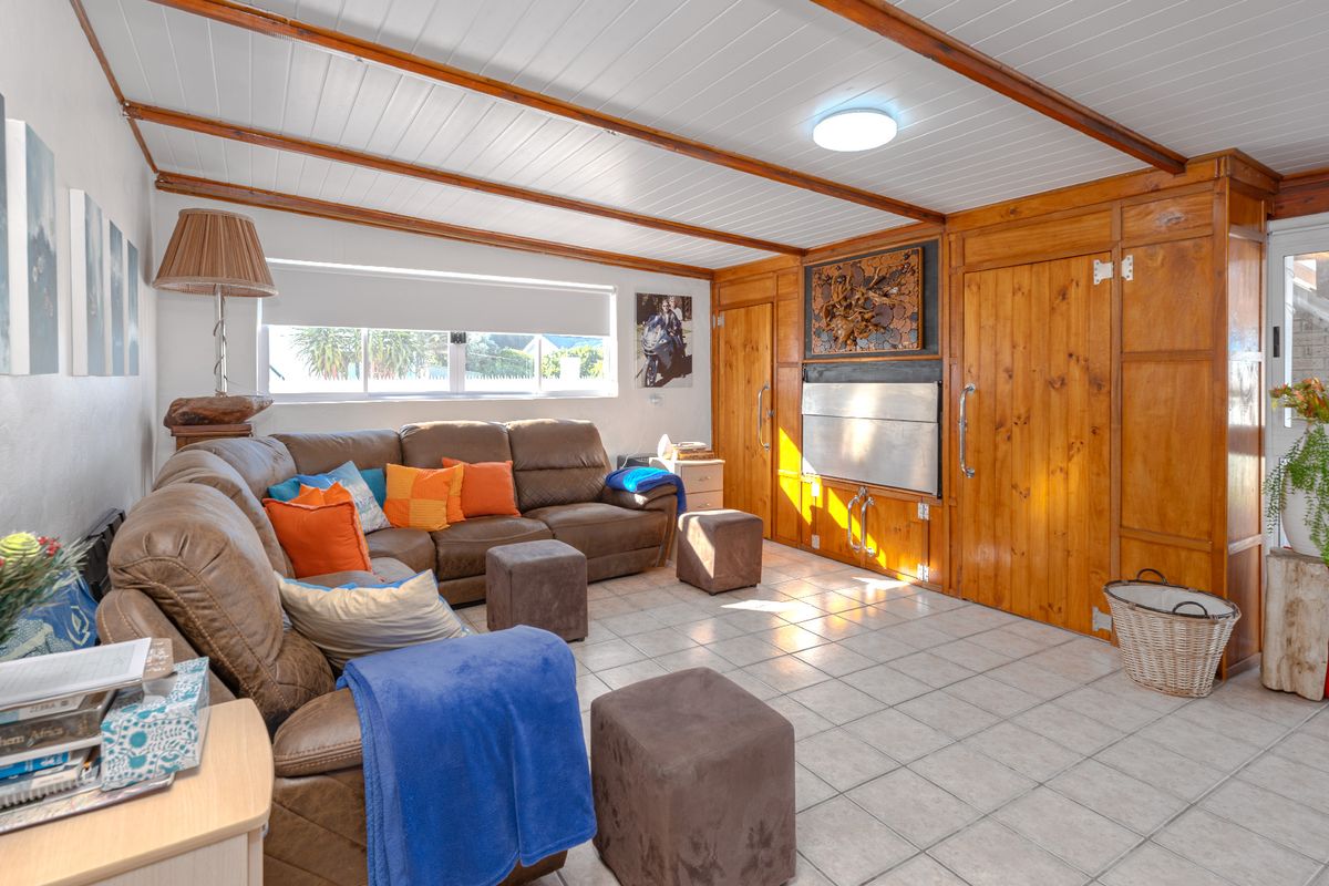 A living room featuring tiled flooring, a timber-paneled ceiling with exposed beams, and extensive built-in timber cabinetry providing integrated storage solutions.