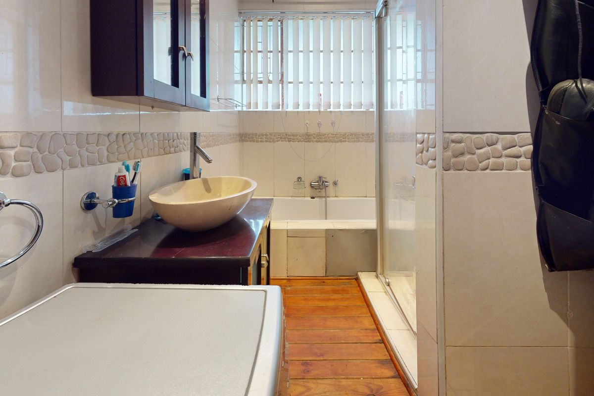 Bathroom featuring a vessel sink on a vanity, a bathtub, and a separate shower enclosure with tiled walls and timber flooring.