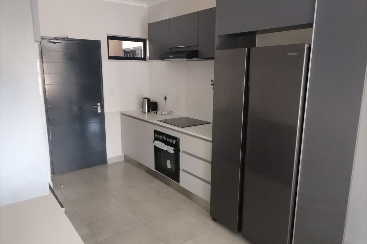Modern kitchen featuring sleek grey cabinetry, built-in oven, electric hob, extractor fan, and tiled flooring.