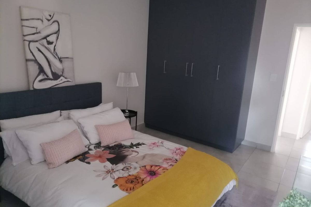 A well-maintained bedroom featuring neutral tiled flooring and a large, dark-toned built-in wardrobe providing ample storage space.